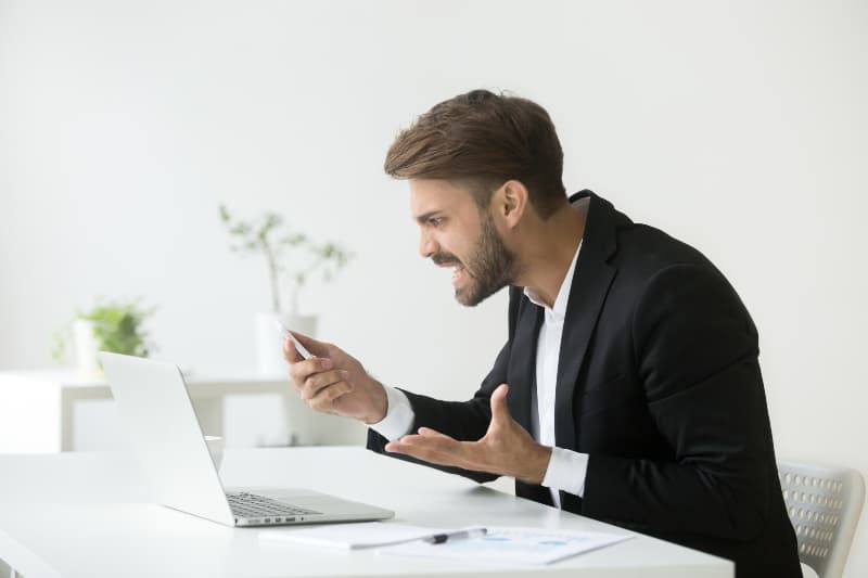 wütender Geschäftsmann, der Telefon hält
