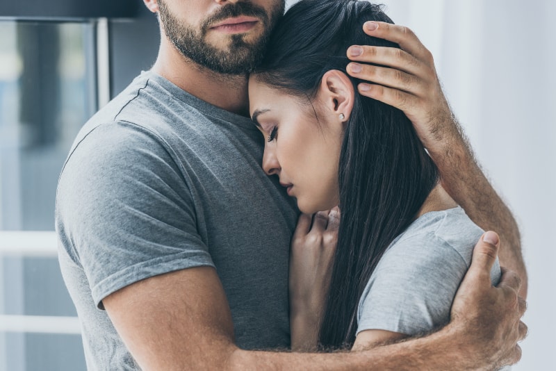 Ein muskulöser Mann umarmt ein weinendes Mädchen