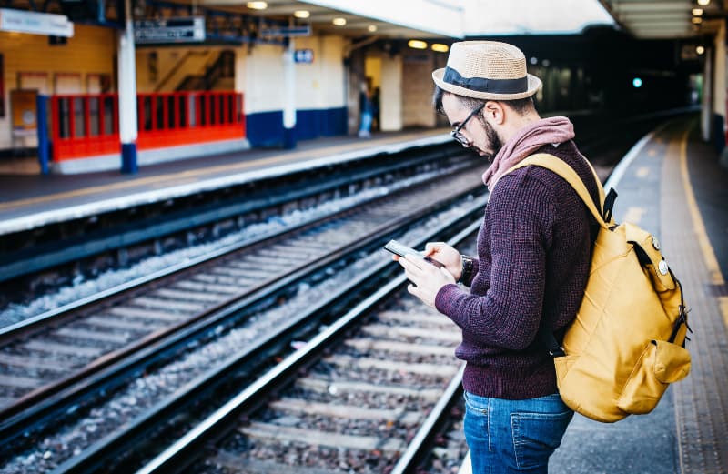 Mann, der Telefon benutzt, während er vor Zug steht
