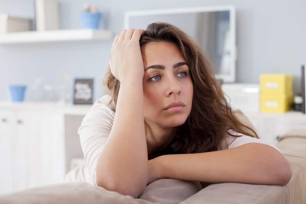 eine schöne Frau, die auf der Couch sitzt und traurig nachdenkt