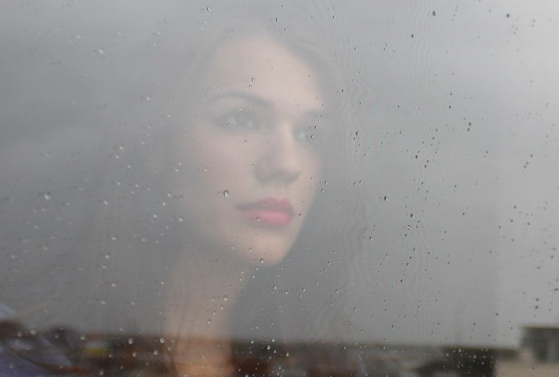 Das Mädchen schaut aus dem regennassen Fenster