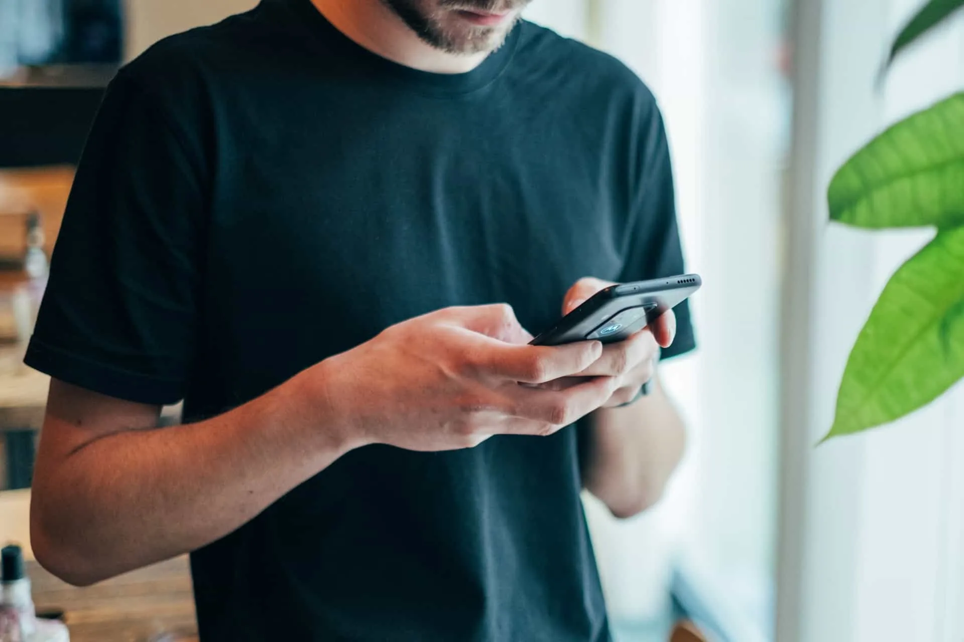 Ein Mann mit Bart im T-Shirt schreibt eine SMS