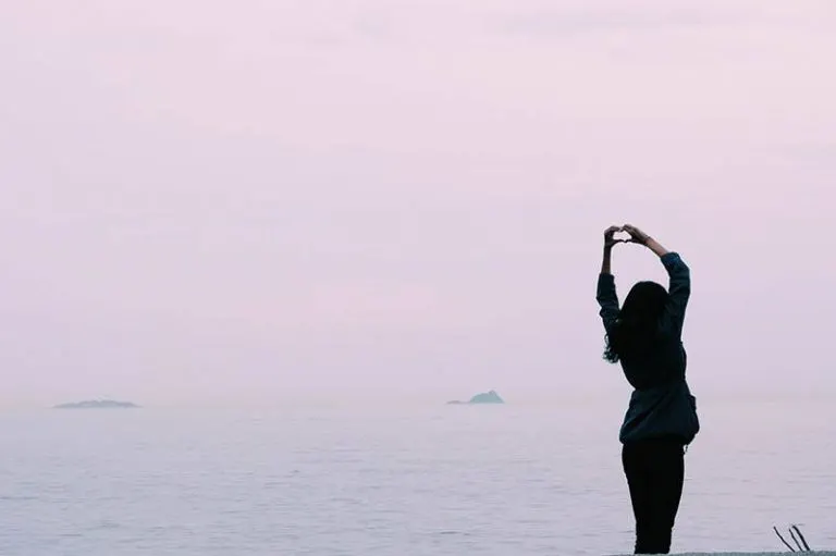 Frau machen Herz mit Händen in der Nähe von Meer