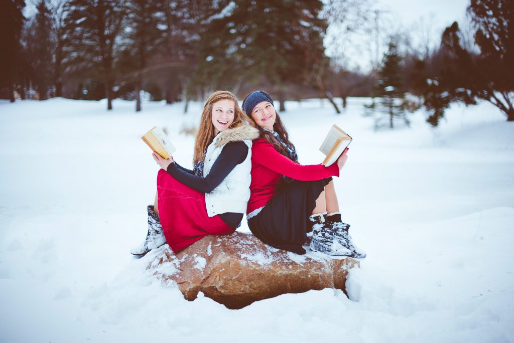 Zwei Frauen sitzen auf einem Felsen und lesen Bücher