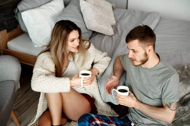 junges Paar im Schlafzimmer mit Kaffee sprechen