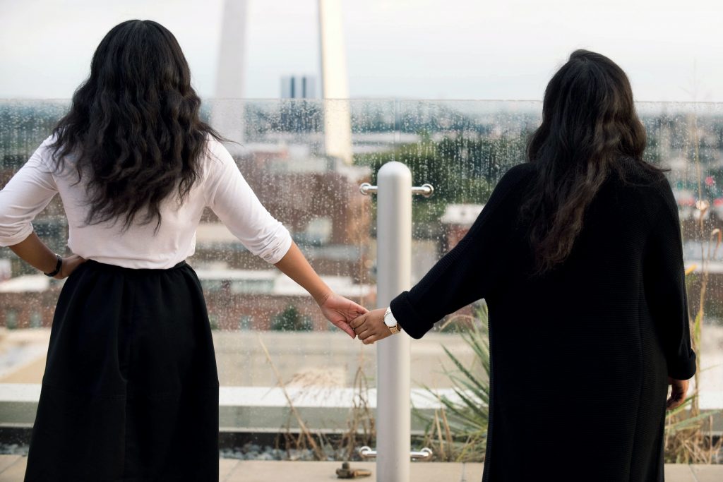 zwei schwarzhaarige Frauen Händchen haltend