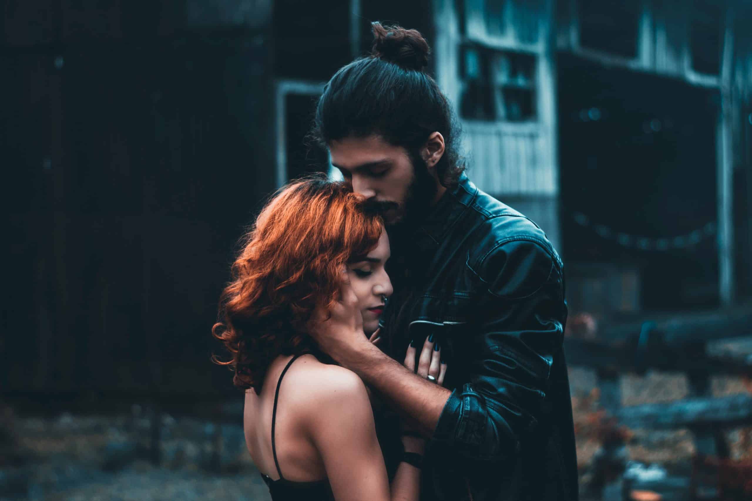 Ein Mann mit längeren Haaren umarmt sanft ein rothaariges Mädchen