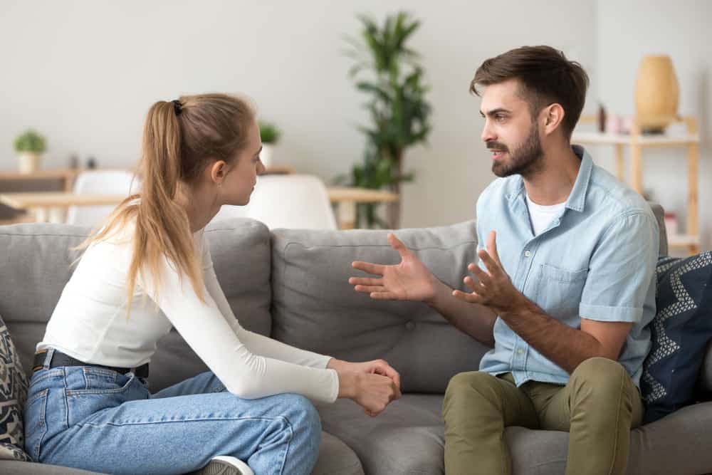 Ein Mann sitzt mit einer Frau auf einer Couch und erklärt ihr etwas