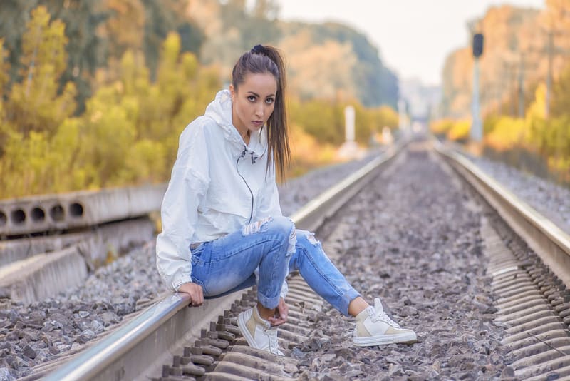 Ein einsames Mädchen in einer weißen Jacke sitzt auf den Bahngleisen