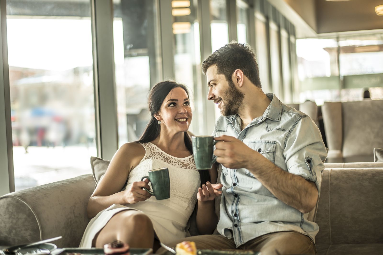 Ein lächelnder Mann und eine Frau sitzen nebeneinander in einem Café