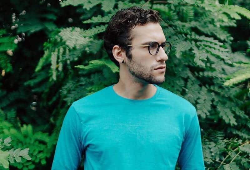 Mann mit Brille und blauem Langarmhemd, das draußen steht