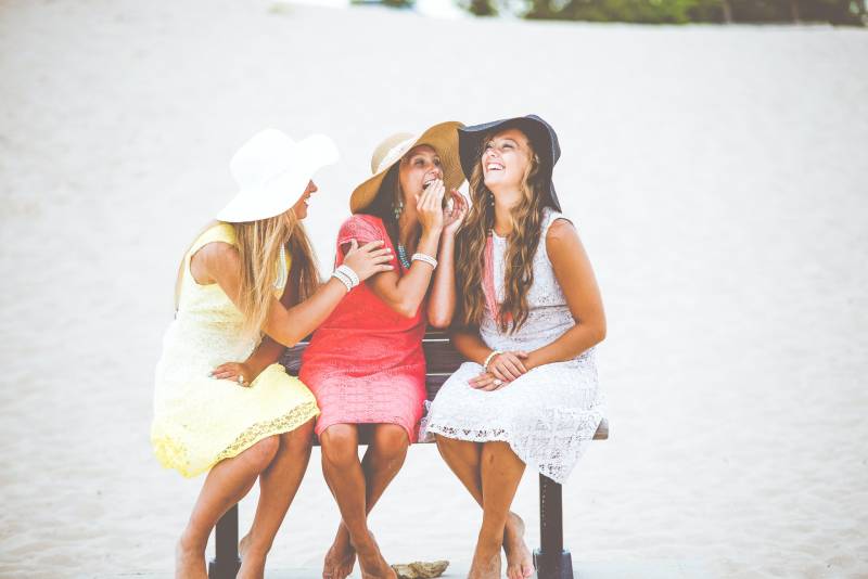 drei Frauen sitzen auf brauner Holzbank