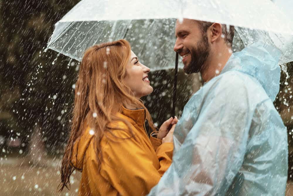 ein lächelndes Paar im Regen unter einem Regenschirm