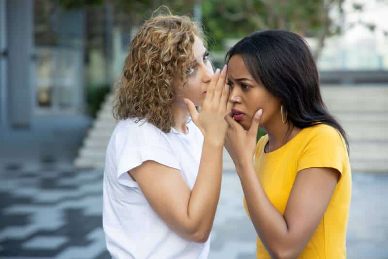 weiße Frauen klatschen und flüstern der schwarzen Frau draußen zu