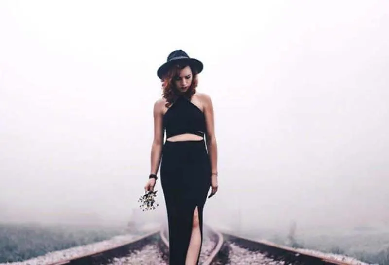 Frau, die schwarzen Hut und schwarzes Kleid trägt, das draußen steht