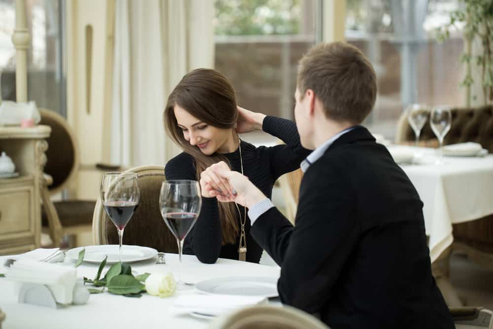 Ein Mann hält die Hand einer Schamfrau, während er zum Mittagessen in einem Restaurant sitzt