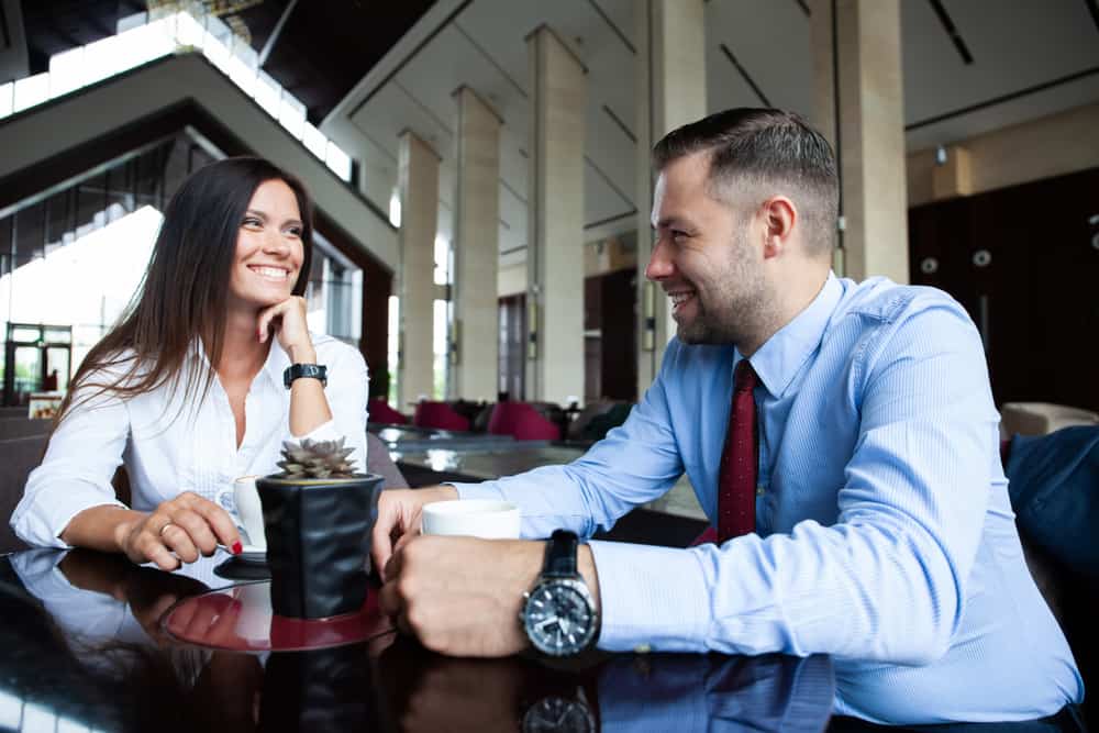 Ein lächelnder Mann und eine lächelnde Frau flirten in einem Café