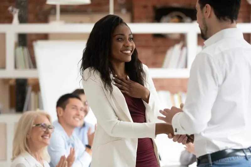 Eine junge schwarze Frau gibt einem Arbeitskollegen die Hand