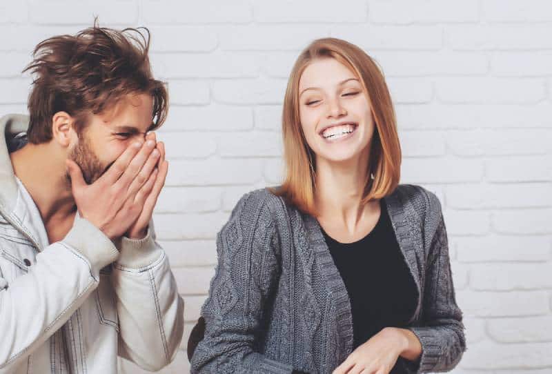 Glückliches junges Paar lachen auf weißem Backsteinhintergrund