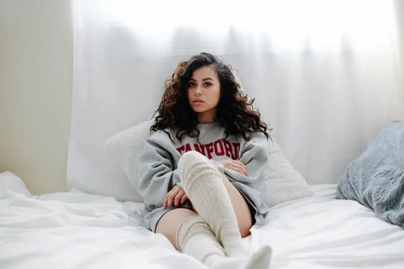 ein Mädchen sitzt auf einem Bett in einem Sweatshirt