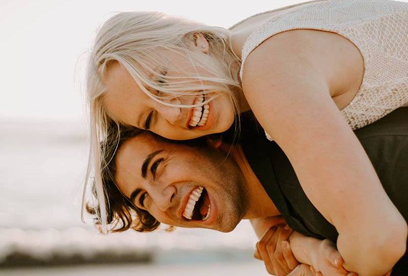 Nahaufnahmefoto des lächelnden Mannes huckepack glückliche blonde Frau draußen