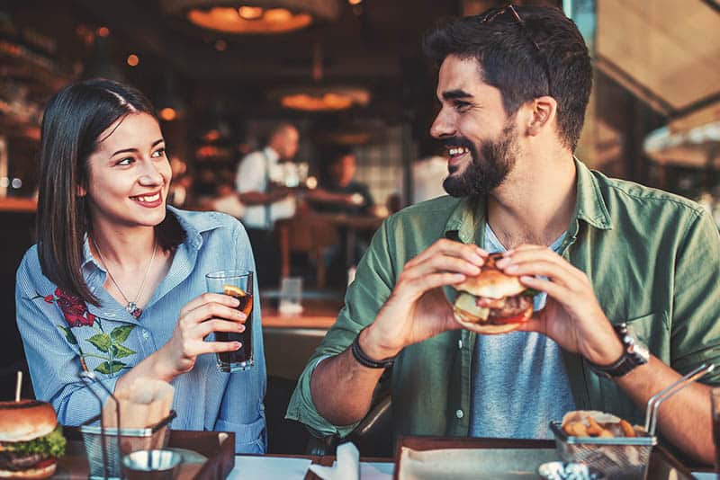 lächelndes junges Paar, das sich im Restaurant schaut