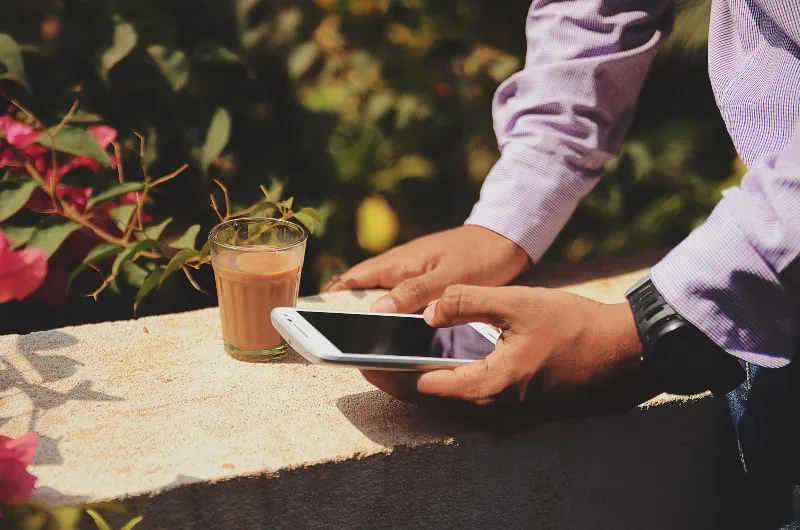 Ein Mann trinkt Kaffee und schreibt eine Nachricht auf sein Handy