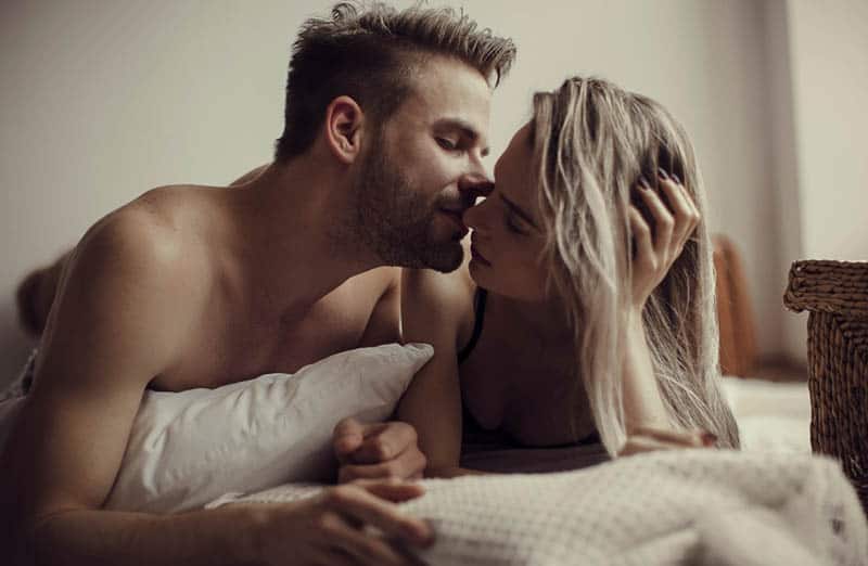 Ein Mann und eine Frau küssen sich zärtlich auf dem Bett