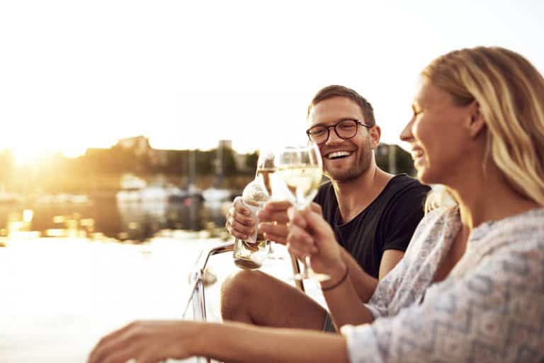 Ein Mann und eine Frau sitzen am Fluss und stoßen an
