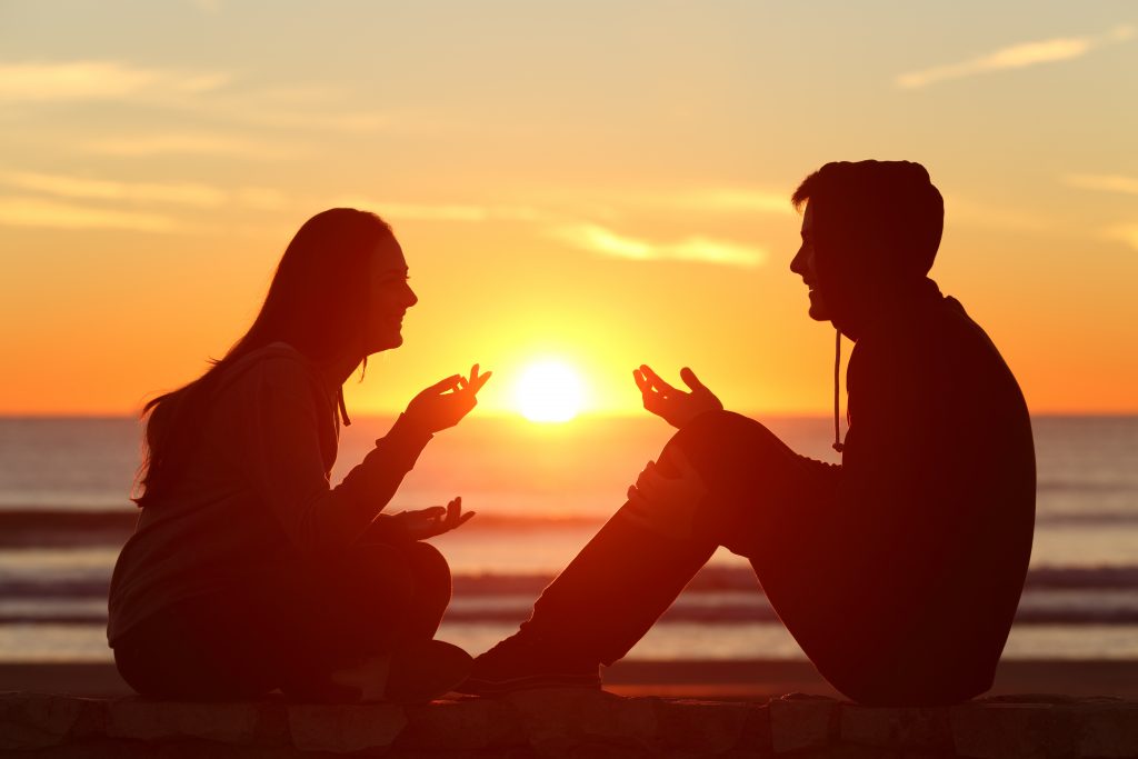 Ein liebevolles Paar sitzt am Strand und redet