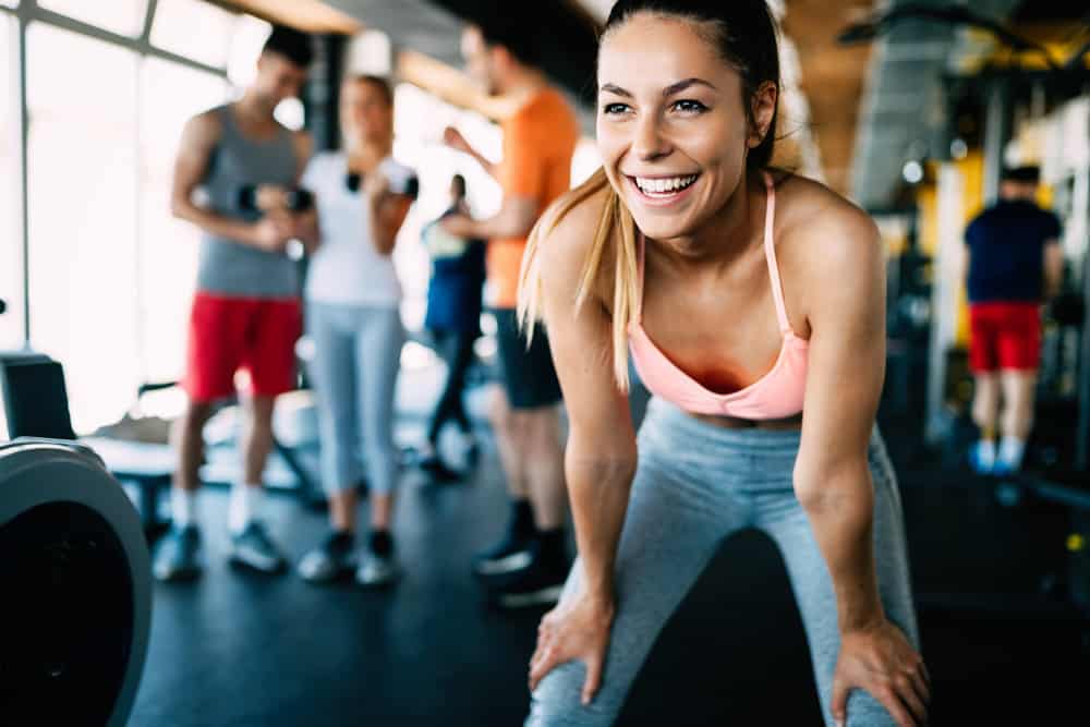 Eine schöne lächelnde Frau im Fitnessstudio steht nackt