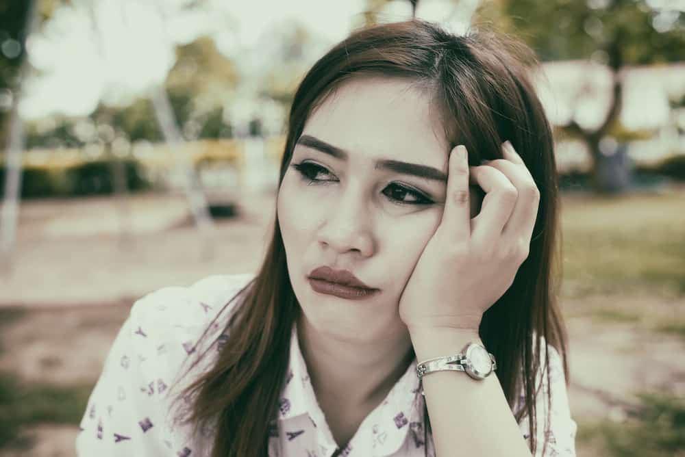 Eine traurige asiatische Frau sitzt draußen