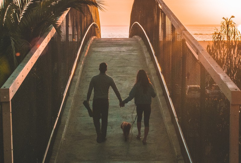 Mann und Frau, die Hand halten, während sie auf Brücke gehen