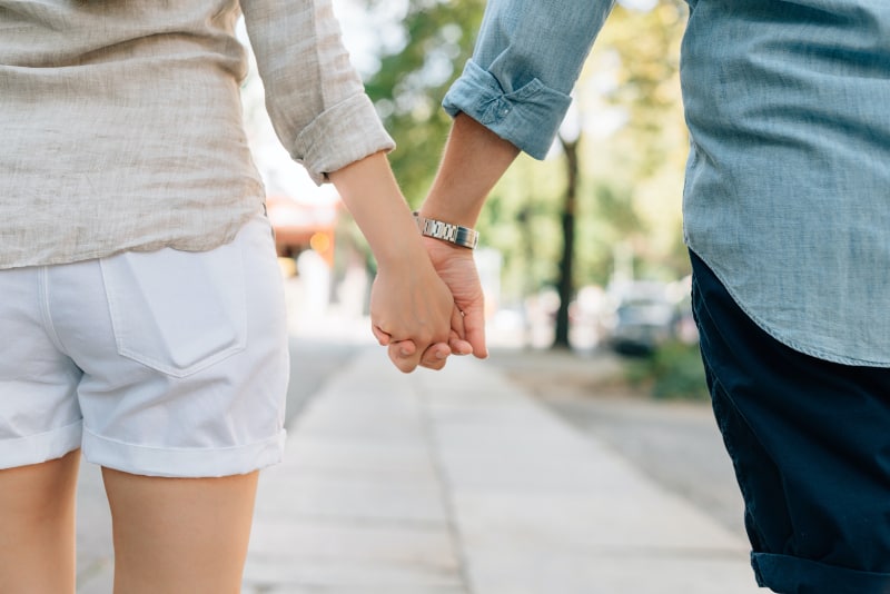 Mann und Frau, die tagsüber Hände im Gehweg zusammenhalten(1)