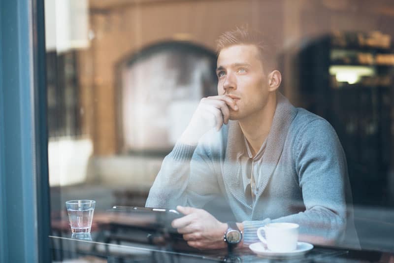 junger Mann, der im Café denkt