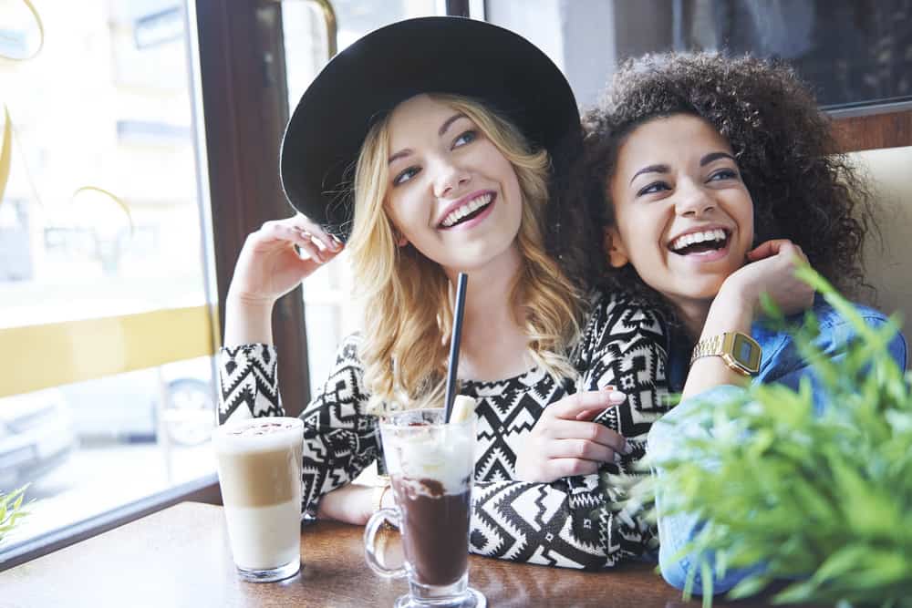 zwei lächelnde Frauen, die in einem Café sitzen