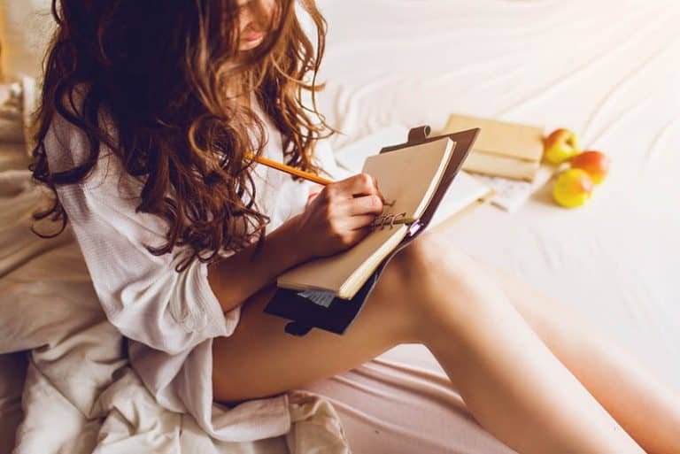 Das Mädchen sitzt auf dem Bett und schreibt ein Tagebuch