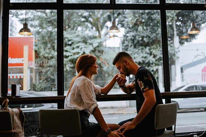 Ein Mann küsst die Hand seiner Frau in einem Café
