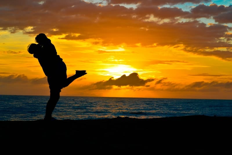 Ein Mann und eine Frau küssen sich bei Sonnenuntergang