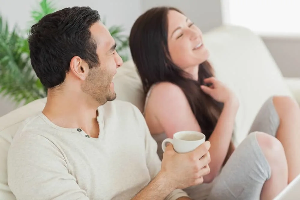 Ein Mann und eine lächelnde Frau sitzen auf der Couch und reden