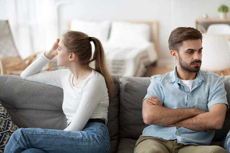 Ein streitender Mann und eine streitende Frau sitzen auf der Couch und schweigen