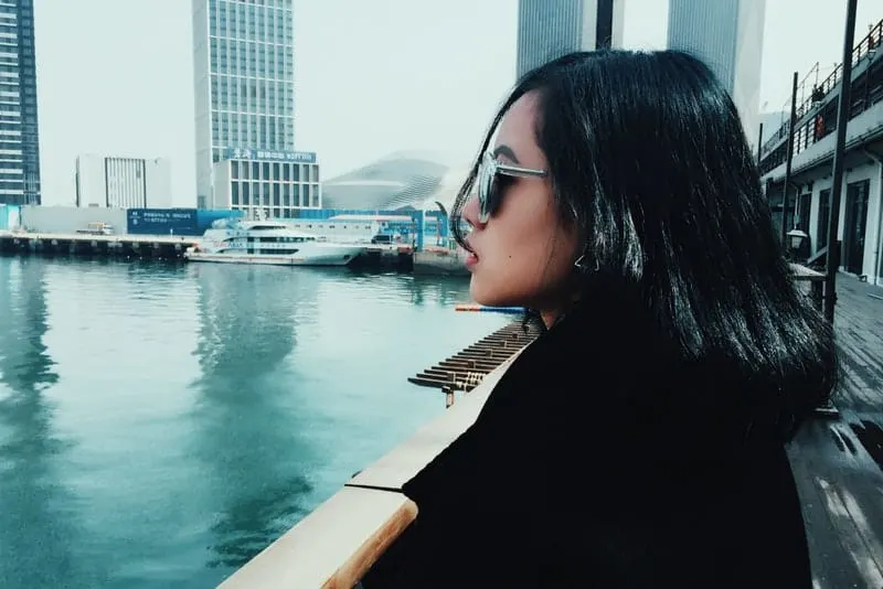 Eine Frau mit Sonnenbrille sitzt in einem Bootshafen