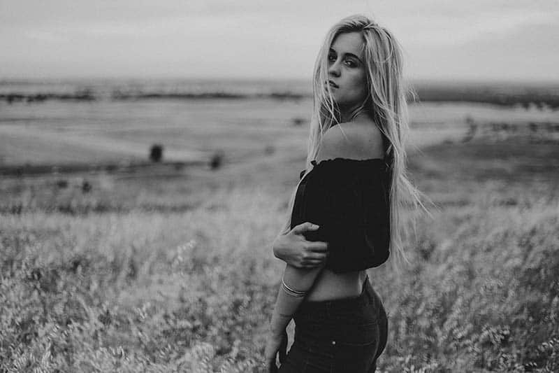 Eine hübsche Blondine steht auf einem Feld
