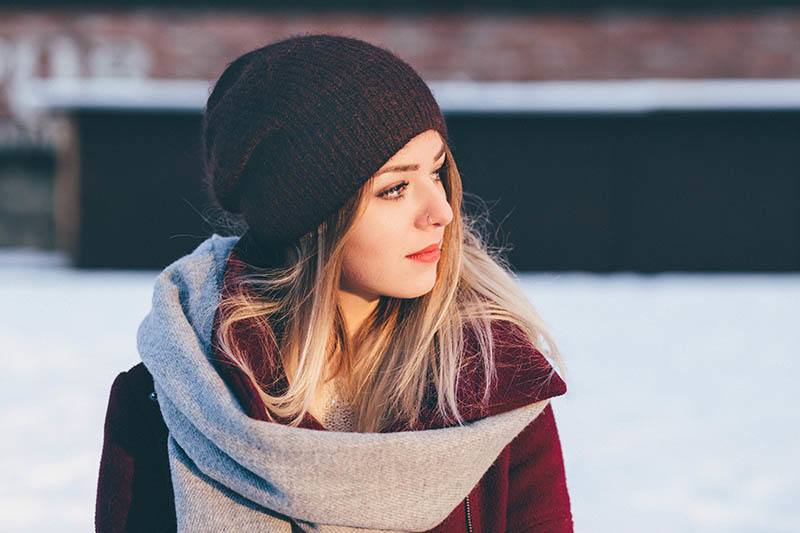 Eine traurige Frau mit einer schwarzen Mütze steht im Schnee und schaut weg