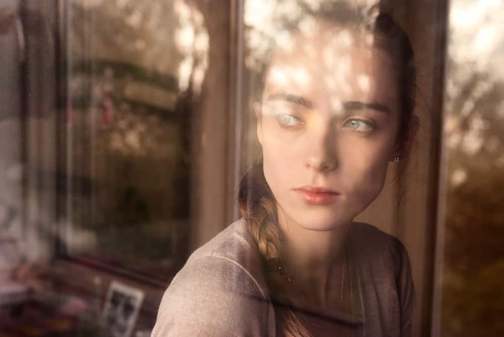 eine schöne traurige Frau, die aus dem Fenster schaut