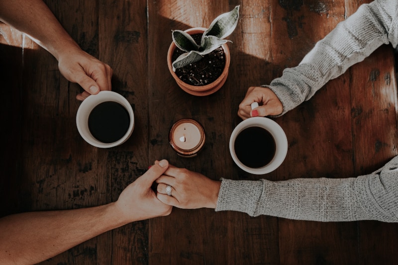 Ein Paar trinkt Kaffee und hält sich an den Händen