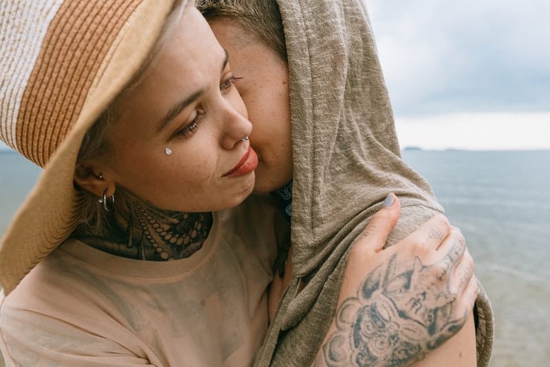 Ein trauriges Mädchen mit einem Tattoo umarmt ihre Freundin