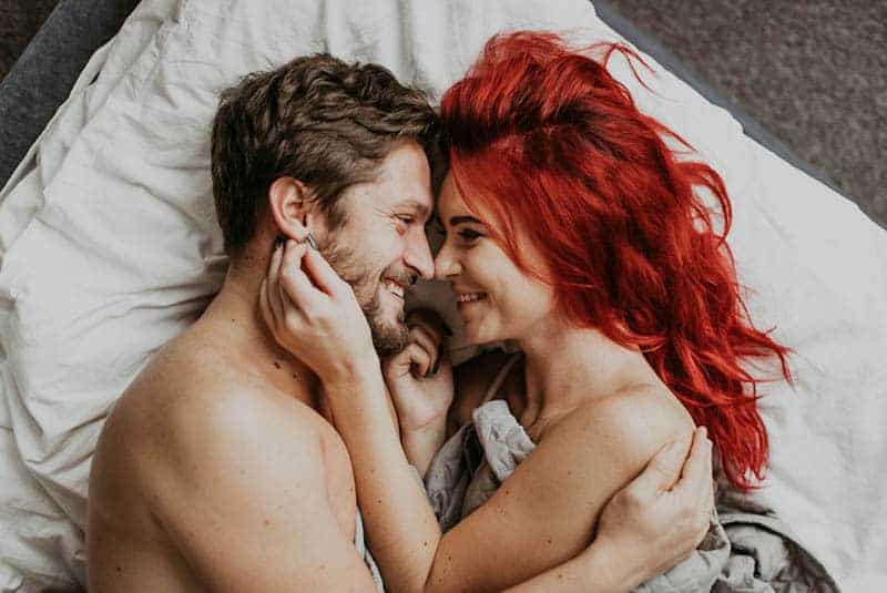 Frau mit roten Haaren, die Manngesicht berühren