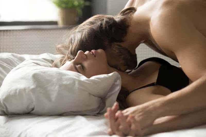 Mann küsst Frau Hals im Bett