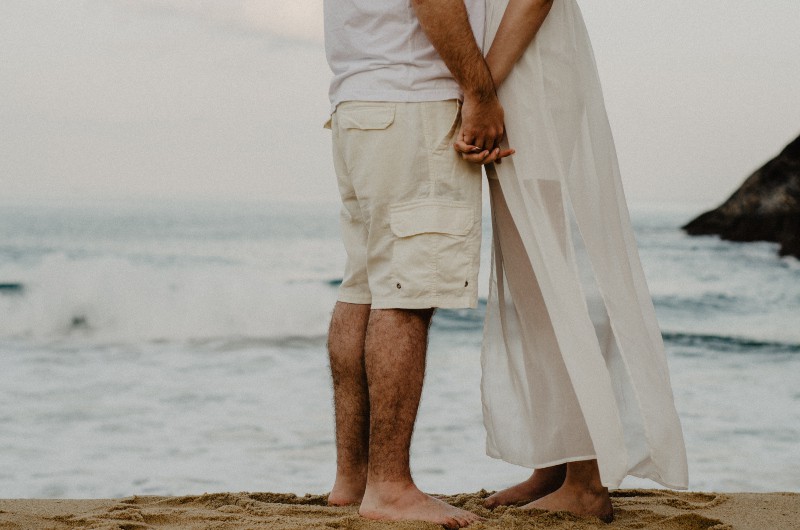 Mann und Frau stehen am Meer, während sie Hände halten